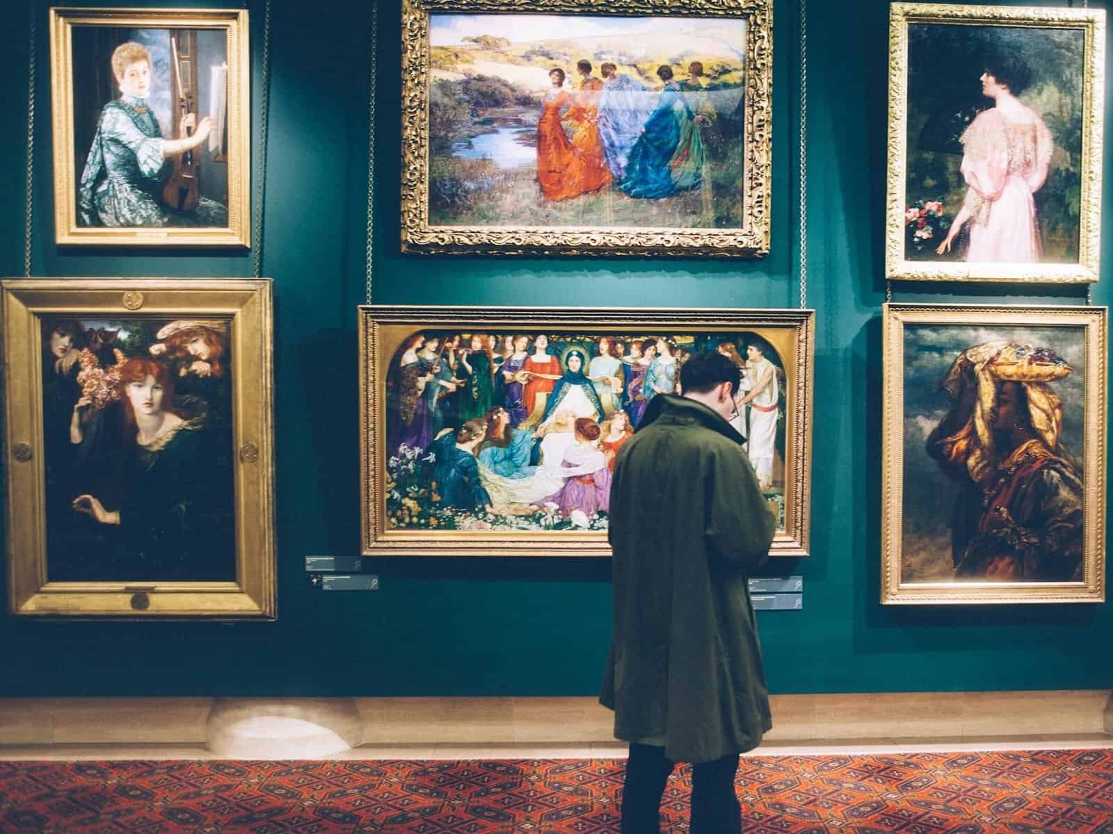 Person views classic artworks in an elegant gallery setting, exploring art history.